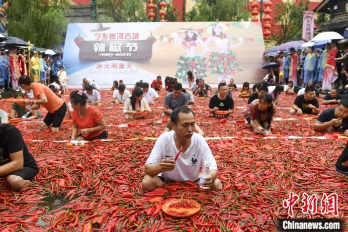 湖南宁乡炭河古城举办吃辣椒挑战赛，众多挑战者坐在铺满辣椒的巨型蓄水池中进行吃辣椒比拼。杨华峰 摄