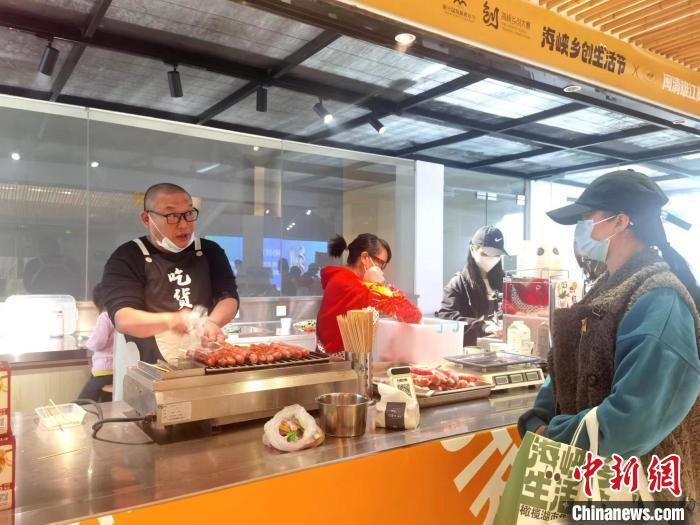 高道明的台湾手工烤肠摊位吸引游客品尝。　郑江洛 摄
