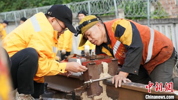 苏永能(右一)在安装焊轨模具后进行严谨的泥沙封箱作业。　谭育俊 摄